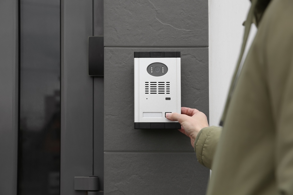 man,ringing,intercom,with,camera,near,building,entrance,,closeup